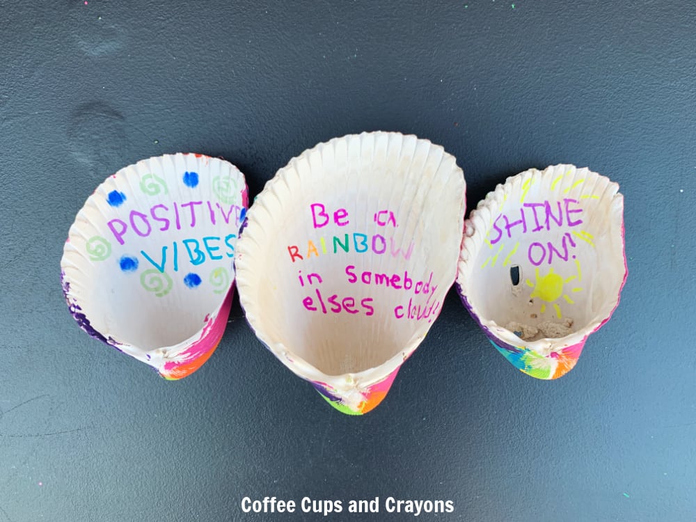inside of 3 seashells with "positive vibes" "Be a rainbow in someone else's cloud" and Shine on" drawn in colorful marker